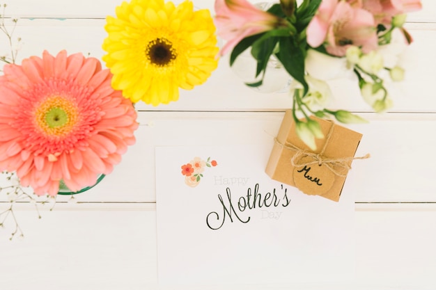 Inscripción de madres con caja de regalo y gerberas.