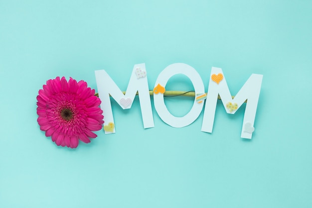 Inscripción de mamá con flor de gerbera en mesa