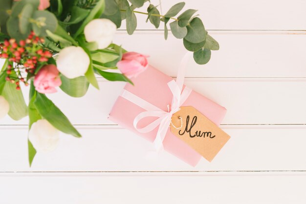 Inscripción de mamá con flores y caja de regalo.