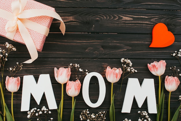 Foto gratuita inscripción de mamá con tulipanes y regalo en mesa