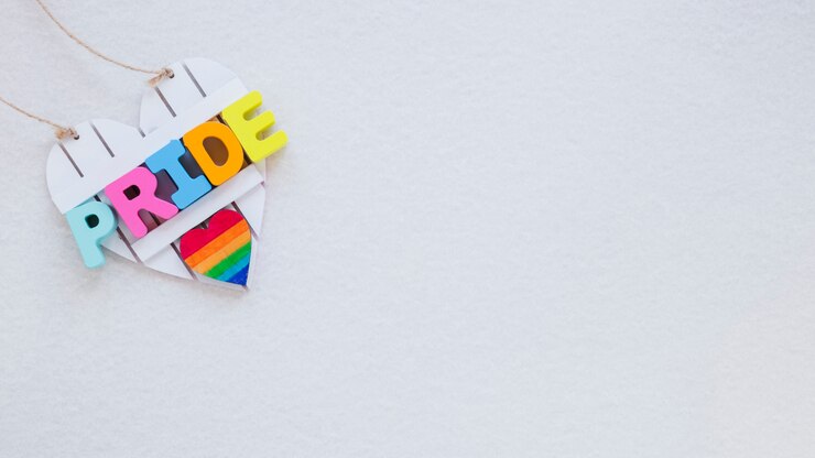 Foto gratuito inscripción de orgullo con el corazón del arco iris en la mesa