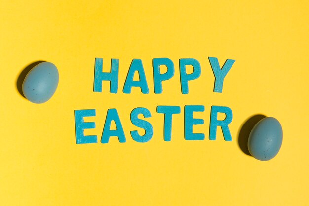 Inscripción de Pascua feliz con huevos coloridos en mesa