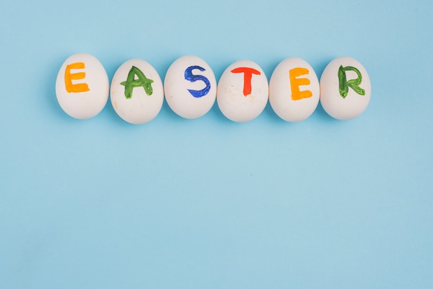 Inscripción de Pascua en huevos en mesa azul