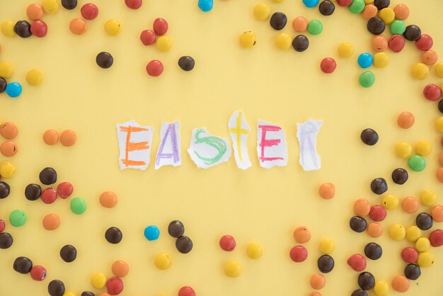 Inscripción de Pascua en papeles cerca de caramelos pequeños.