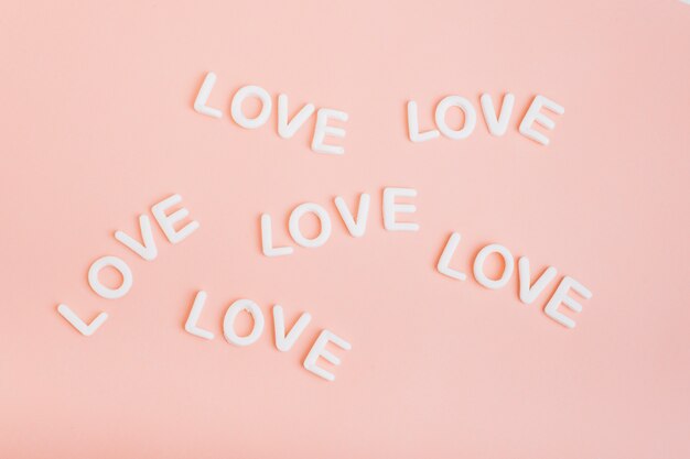Inscripciones blancas de amor en mesa rosa.