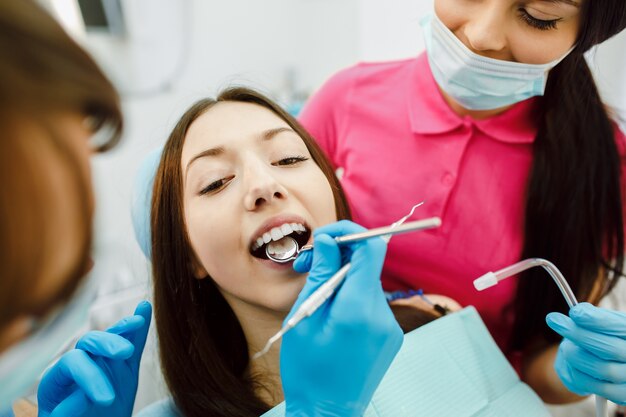 Inspección de los dientes de la mujer con la ayuda de un espejo.