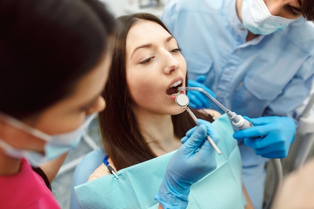 Inspección de los dientes de la mujer con ayuda de un espejo.