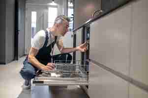 Foto gratuita instalaciones de cocina perfil del hombre tocando detalles en la cocina iluminada por la luz del día