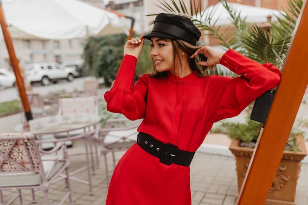 Instantánea en estilo parisino de joven fashionista. Chica con cómodo corte de pelo corto posa audazmente para la foto de la calle