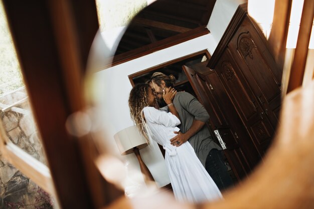 Instantánea de pareja de enamorados en acogedor piso. Chico y chica abrazándose con sonrisa.