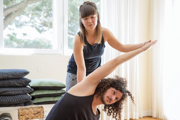Instructor ayudando al hombre a hacer una curva lateral en la clase de yoga