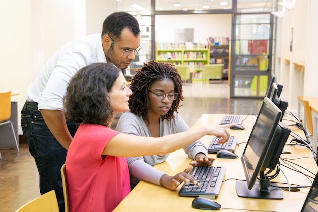 Instructor ayudando a estudiantes en clase de computación