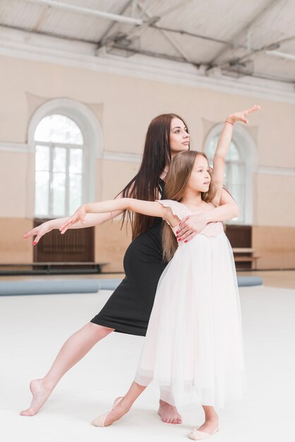 Instructor de bailarina y niña poising en estudio de danza