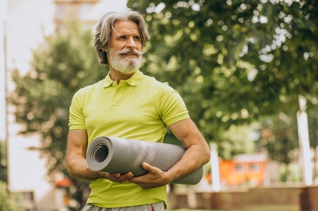 Instructor de yoga de mediana edad con mat en el parque