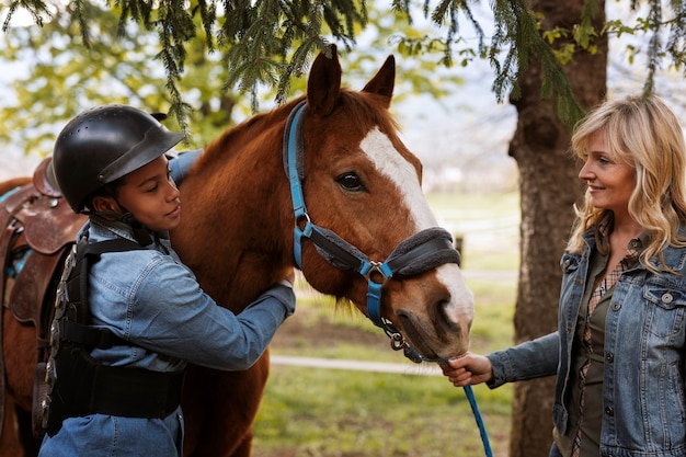 Instructora ecuestre femenina enseñando a los niños a montar a caballo