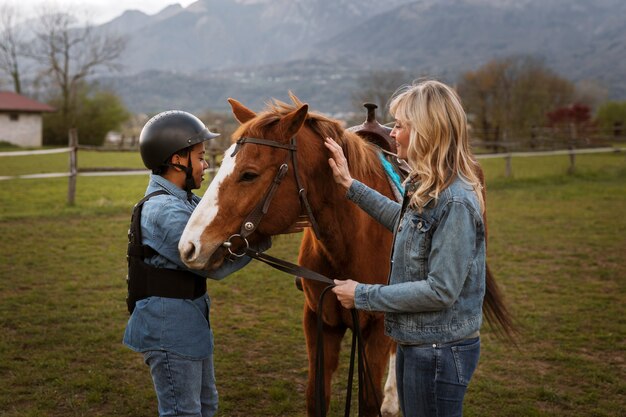 Instructora ecuestre femenina enseñando a los niños a montar a caballo