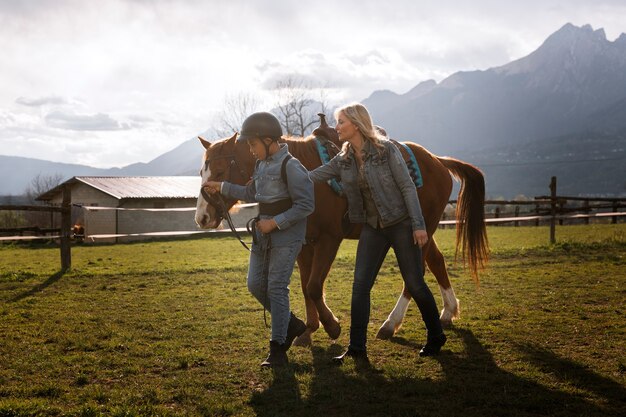 Instructora ecuestre femenina enseñando a los niños a montar a caballo