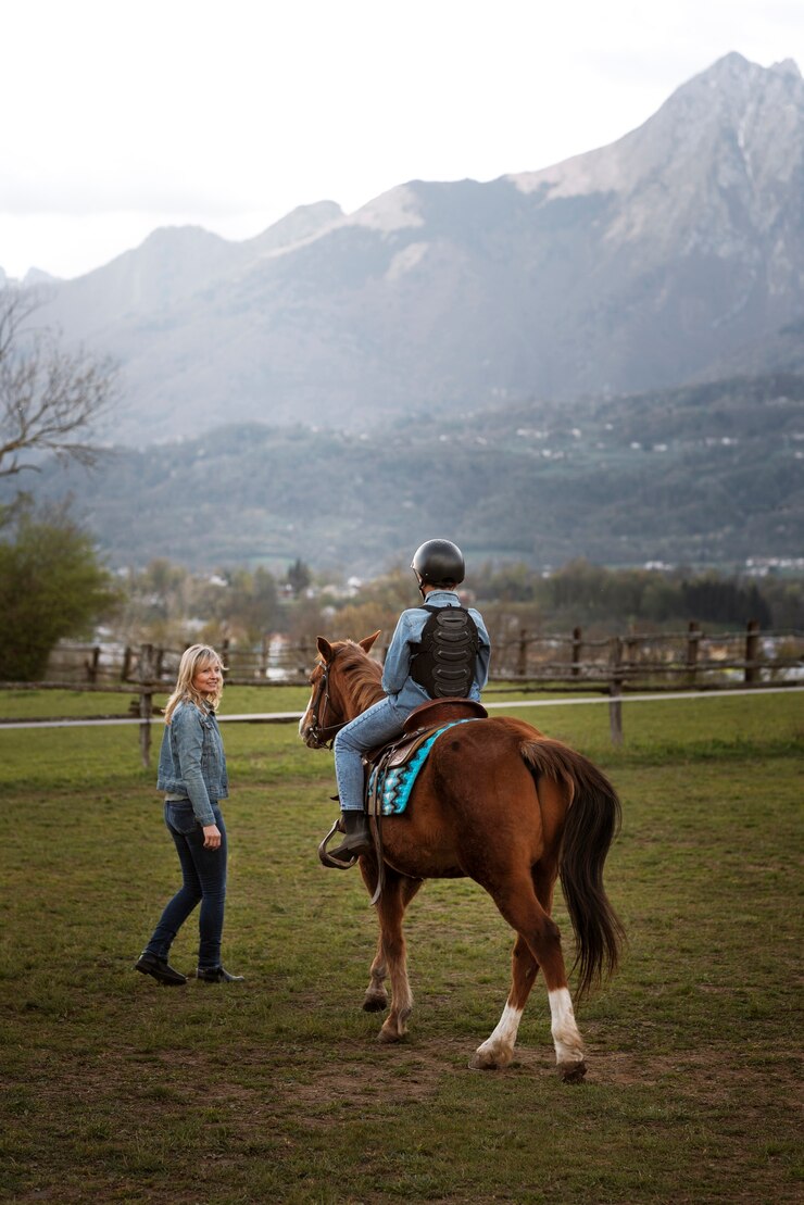 Foto gratuito instructora ecuestre femenina enseñando a los niños a montar a caballo