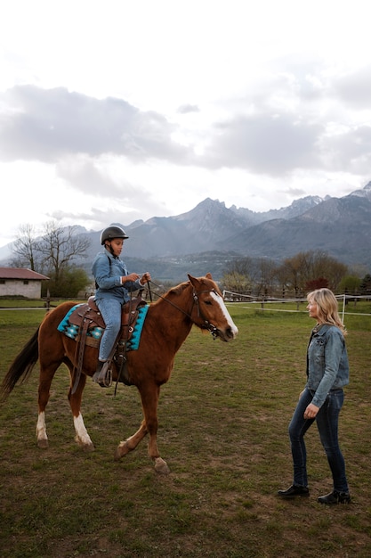 Instructora ecuestre femenina enseñando a los niños a montar a caballo