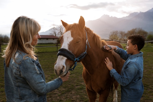 Instructora ecuestre femenina enseñando a los niños a montar a caballo