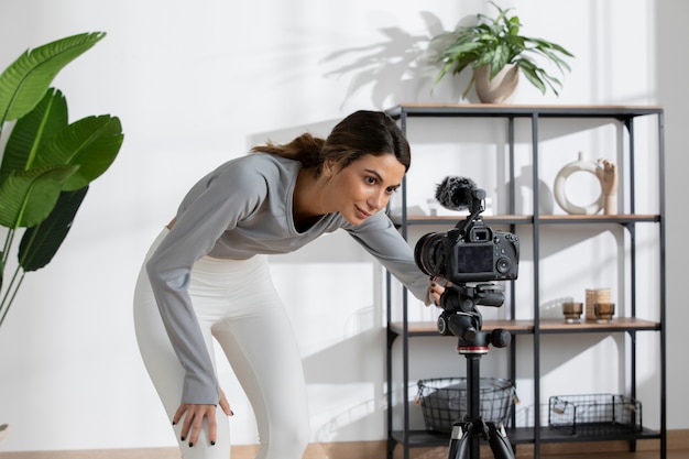 Foto gratuita instructora de fitness femenina configurando una cámara en casa para dar clases en línea