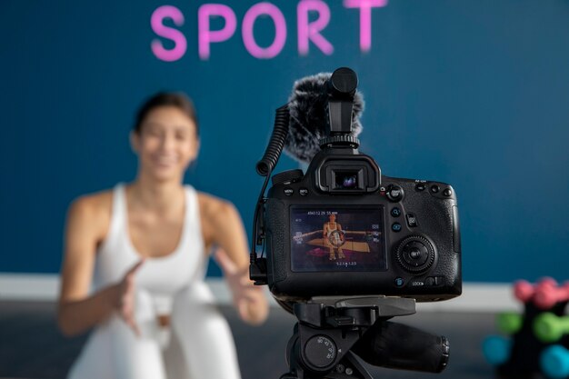 Instructora de fitness femenina enseñando una clase en casa mientras usa la cámara en un trípode