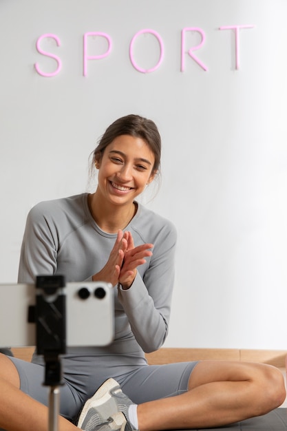 Instructora de fitness femenina enseñando una clase en línea desde casa usando un teléfono inteligente