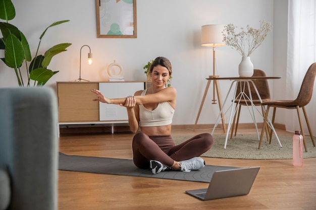 Instructora de fitness femenina que usa una computadora portátil para enseñar una clase desde casa