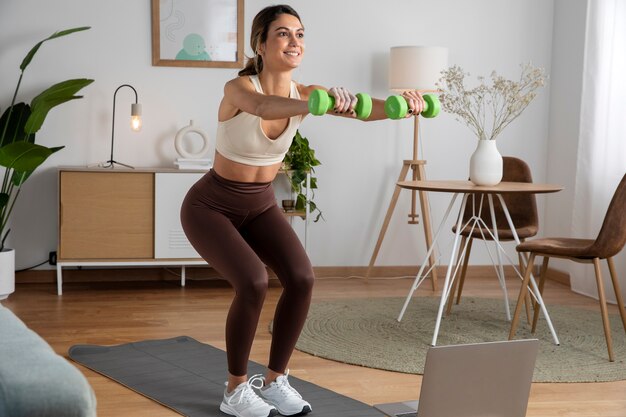 Instructora de fitness femenina que usa una computadora portátil para enseñar una clase desde casa