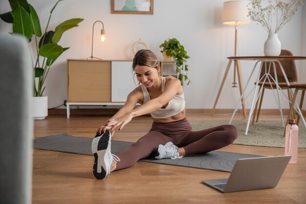 Instructora de fitness que usa una computadora portátil para enseñar una clase desde casa