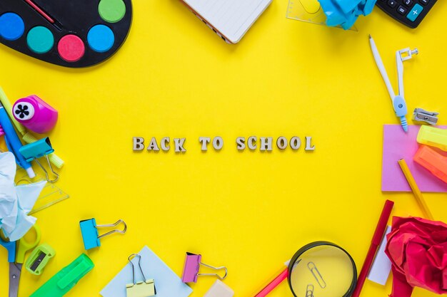 Instrumentos de escritura colocados en círculo con palabras de regreso a la escuela