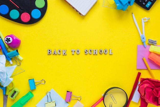 Instrumentos de escritura colocados en círculo con palabras de regreso a la escuela