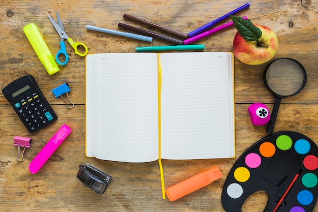 Instrumentos de escritura y manzana en círculo con el cuaderno en el medio