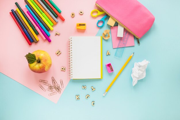 Instrumentos de escritura y manzana colocados de forma aleatoria