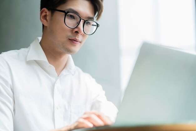 Inteligente, atractivo, positivo, hombre de negocios asiático, con gafas, trabajo remoto, nuevo estilo de vida normal, uso manual, portátil, teleconferencia, videollamada en vivo, reunión, concepto de ideas de negocios remotos.