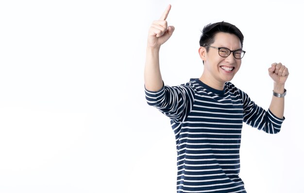 Inteligentes y atractivas gafas asiáticas, la mano masculina se levanta alegre, salió de pie y sonríe con frescura y alegre camisa azul casual, retrato de fondo blanco.