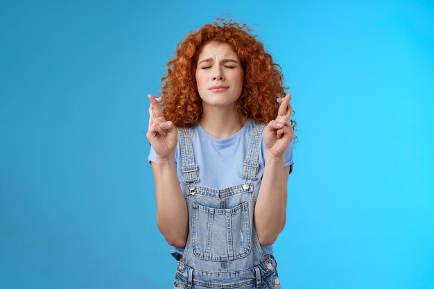 Intensa pelirroja atractiva nerviosa de cabello rizado esperanzada enfocada niña orando suplicando pidiendo a Dios que haga el sueño realidad cruzar los dedos buena suerte anticipando noticias importantes quiero desear cumplir.