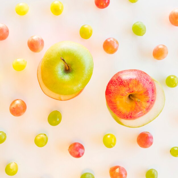 Intercambia rebanadas de manzana verde y roja rodeadas de uvas sobre fondo blanco