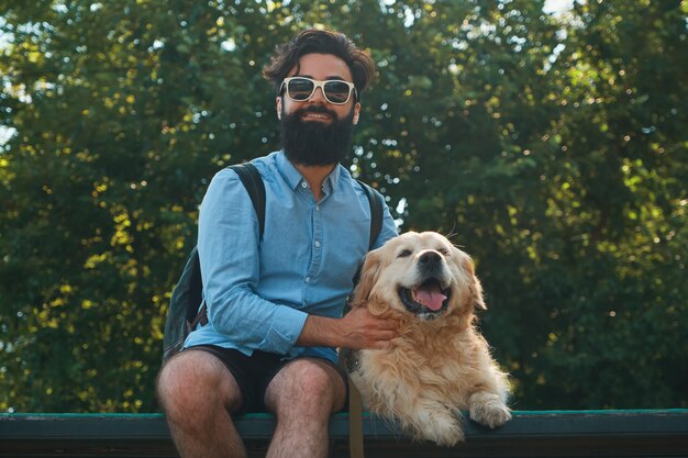 Interesante hombre sentado con su perro en la silla en el parque