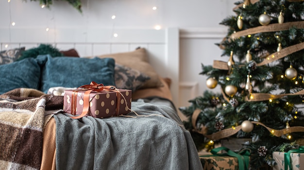Interior de una acogedora habitación con un árbol de navidad y una caja de regalo en la cama Foto Premium 
