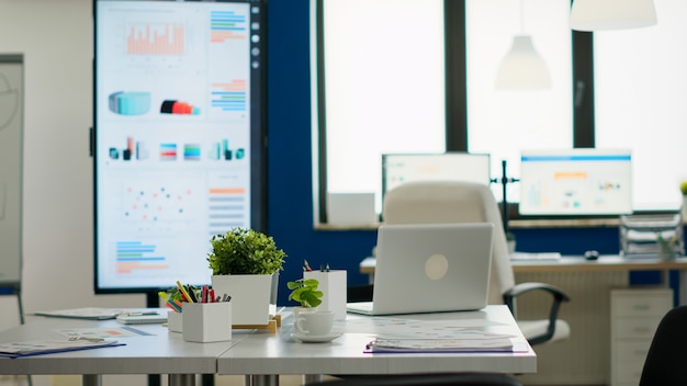 Interior de la acogedora sala de empresa luminosa con mesa de conferencias lista para la lluvia de ideas, sillas modernas y elegantes y monitor de escritorio, todo listo para los empleados. Oficina espaciosa vacía de espacio de trabajo creativo.