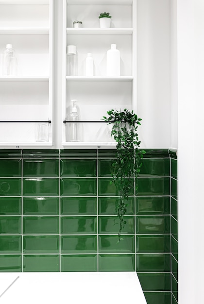 Foto gratuita interior de baño con azulejos verdes y gabinetes blancos en la pared.