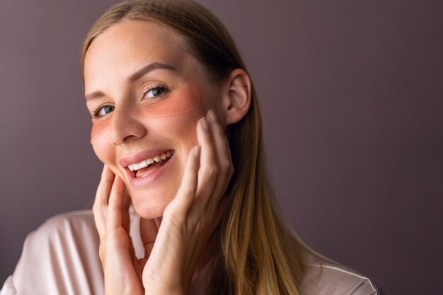 Interior de cerca retrato de mujer rubia hacer rutina de cuidado de la piel, uso de parches en los ojos, concepto de spa en casa. Anti edad.