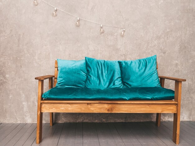 Interior de pared gris con elegante sofá tapizado en azul y madera moderno, lámparas colgantes