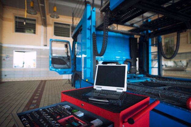 Interior del taller de camiones con carrito de herramientas y herramienta de diagnóstico de computadora portátil para reparar vehículos de camión