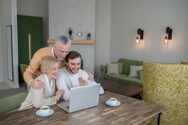 En Internet. Familia sentada en la computadora portátil y tener una videollamada