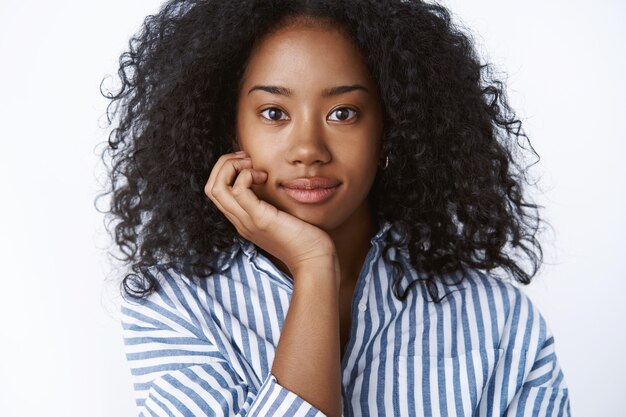 Intersted atractiva joven estudiante universitaria afroamericana de pelo rizado asistir a una conferencia interesante con la cabeza inclinada hacia la palma de la mano mirando intrigado curioso escuchando satisfecho sonriendo, mirando feliz