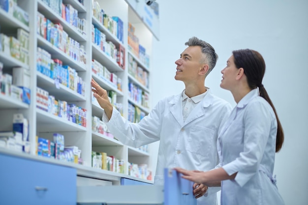 Inventario. Dos farmacéuticos en batas de laboratorio en el proceso de inventario en una farmacia