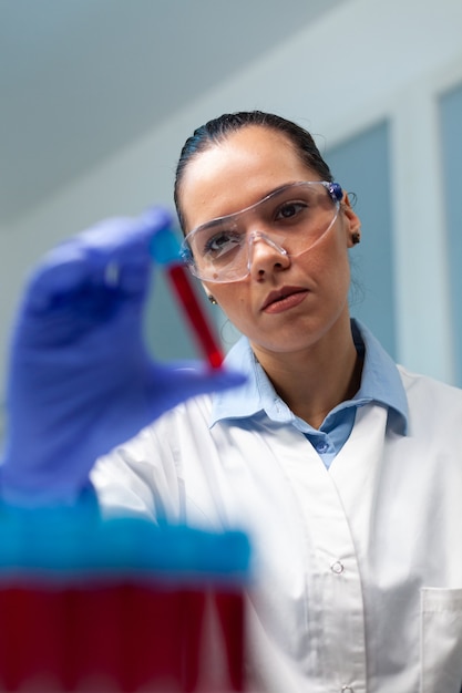 Investigador biólogo mujer sosteniendo vacutainer de sangre analizando durante el experimento científico