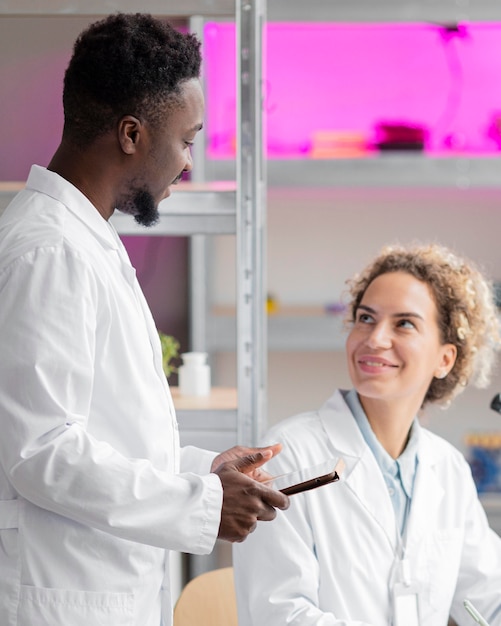 Investigador masculino y femenino conversando en el laboratorio